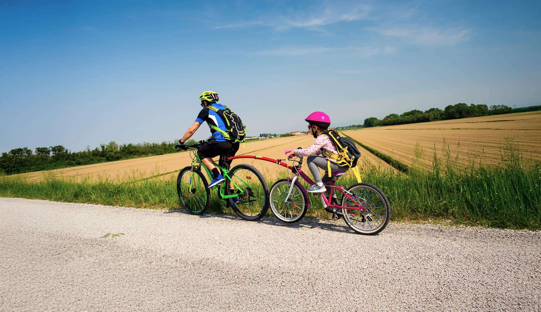 Father and child riding with their bicycles tied together